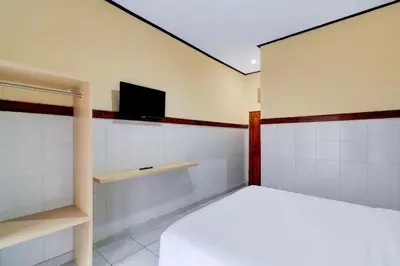 a bedroom with a bed and a tv on the wall at Townhouse Oak @lebak Bene Near Kuta Beach in Balian