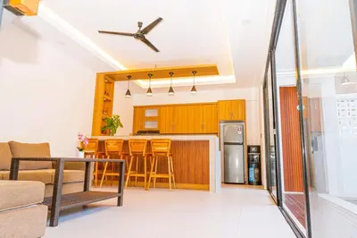a living room with a kitchen and a bar with stools at Brand New! Villa Putu Seminyak in Kerobokan