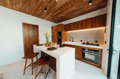 a kitchen with a white counter and wooden cabinets at La Payesa 2 in Canggu