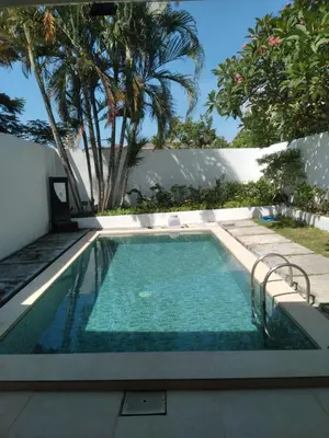 a swimming pool with blue water in a backyard at Villa Private In Kuta Bali in Kuta