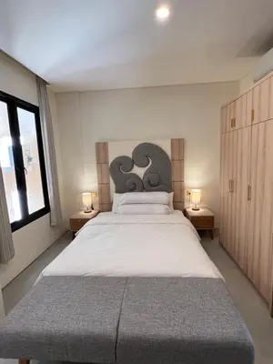 a bedroom with a large white bed with two lamps at Luminera Bali Apartment in Nusa Dua