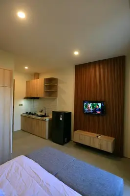 a room with a bed and a kitchen with a tv at Luminera Bali Apartment in Nusa Dua
