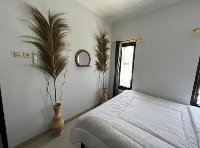 a bedroom with a bed and two plants in vases at Omah Chandra in Pesanggaran