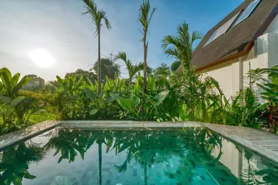 a swimming pool in front of a house with palm trees at New! Architectural 2BR Villa near Seminyak in Kerobokan