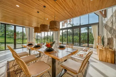 a dining room with a table and chairs and windows at New! Architectural 2BR Villa near Seminyak in Kerobokan