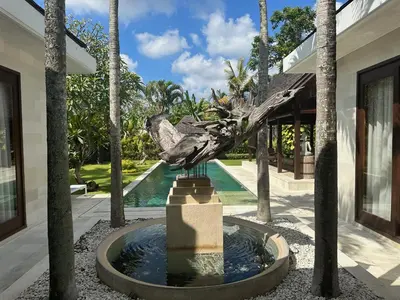 a statue in front of a house with palm trees at Saba Villas in Canggu