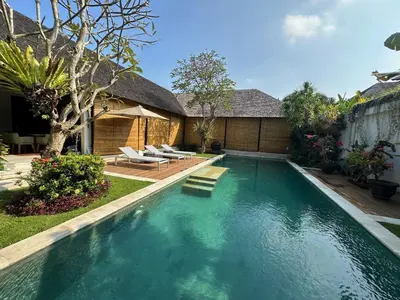 a swimming pool with chairs and a house at Saba Villas in Canggu