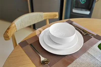a white cup and plate on a wooden table at Levora by Kozystay - Nusa Dua in Nusa Dua
