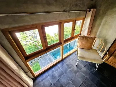 a room with a chair and a large window at Villa Hibou - New Tropical Luxury 2BR near Canggu in Canggu