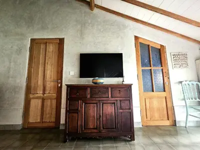 a tv on a wooden cabinet in a room with a door at Villa Hibou - New Tropical Luxury 2BR near Canggu in Canggu
