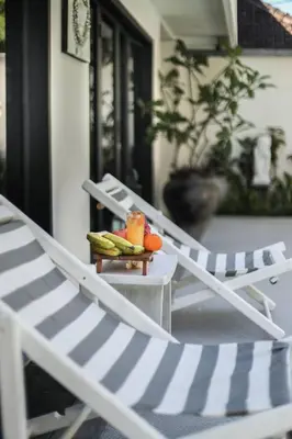 two lounge chairs sitting on a porch with a tray of fruit at Villa Drupadi 16 in Seminyak