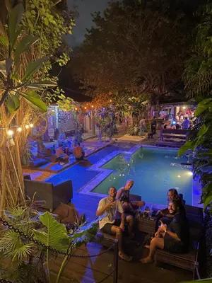 a group of people sitting around a pool at night at Da Housetel Kuta in Kuta