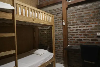 a bedroom with two bunk beds and a brick wall at Da Housetel Kuta in Kuta