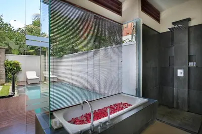 a bathroom with a large bath tub with a window at Royal Samaja Villas in Seminyak