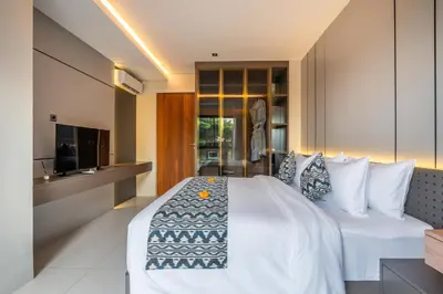 a bedroom with a white bed and a kitchen at Villa Narda Seminyak by Nagisa Bali in Legian