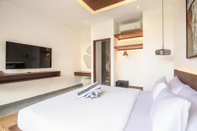 a bedroom with a white bed and a tv at Stunning 5BR Canggu Villa 400m from the Beach in Canggu
