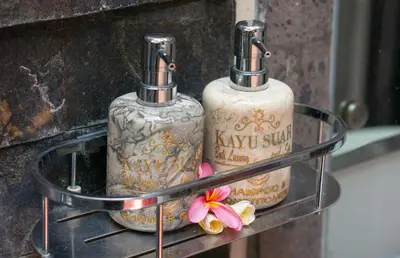 two bottles on a glass table with flowers on it at Kayu Suar Bali Luxury Villas & Spa in Sanur