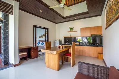 an open kitchen with a wooden table and a dining room at Kayu Suar Bali Luxury Villas & Spa in Sanur
