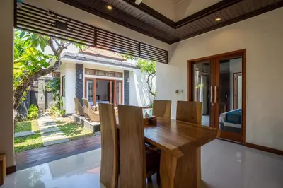 a dining room with a wooden table and chairs at Kayu Suar Bali Luxury Villas & Spa in Sanur
