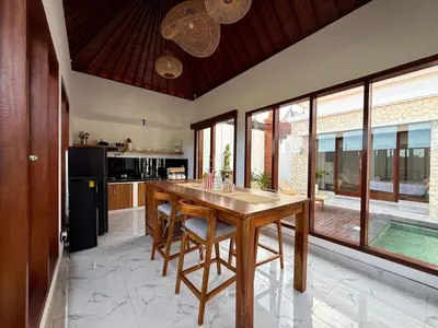 a kitchen with a wooden table and some windows at Chic Villa at Kubu Taullan 3B in Kerobokan