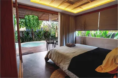 a bedroom with a bed and a balcony with a pool at Kayunida - Charming 1BR Wooden Villa in Seminyak in Seminyak