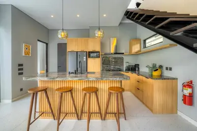 a kitchen with wooden stools and a counter top at Rooftop Villa Elegant 4BR Retreat in Umalas in Kerobokan