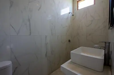 a white bathroom with a toilet and a sink at Casa Ombak in Kerobokan
