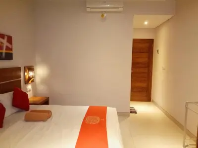 a bedroom with a bed with an orange blanket on it at Pondok Sutya in Kuta