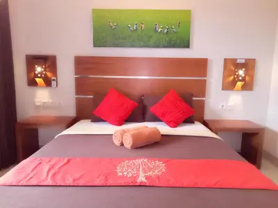 a bedroom with a large bed with red pillows at Pondok Sutya in Kuta