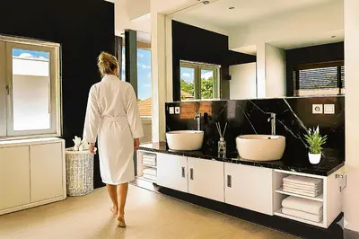 a woman walking through a bathroom with two sinks at Villa Avrora Batubelig in Canggu