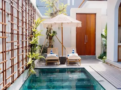 a swimming pool with two chairs and an umbrella at Arjuna Villa in Seminyak