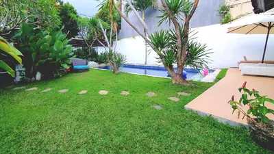 a yard with a swimming pool with a tree in it at Villa Umah JD Umalas 3 kamar private pool in Canggu