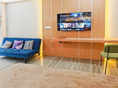 a living room with a blue couch and a tv at Lavaya Resort 1BR Nusa Dua Pool, WiFi, Netflix in Nusa Dua