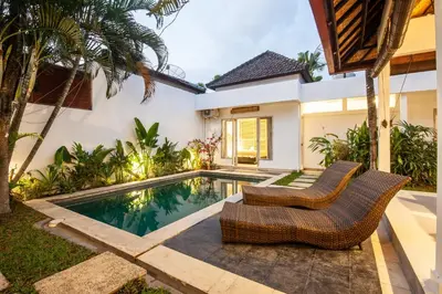 a villa with a swimming pool and two chairs at Homey Villa 2BR Seminyak in Seminyak