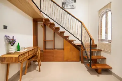 a hallway with wooden stairs and a wooden desk at Cozia Living in Jimbaran
