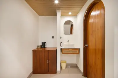 a bathroom with a sink and a wooden door at Cozia Living in Jimbaran