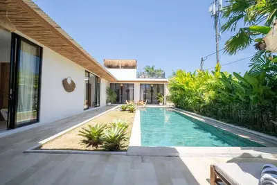 an external view of a villa with a swimming pool at Villa Amie Elegant 5BR with Pool & Rooftop Umalas in Canggu