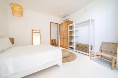 a white bedroom with a bed and a chair at Villa Amie Elegant 5BR with Pool & Rooftop Umalas in Canggu