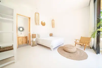 a white room with a bed and a mirror at Villa Amie Elegant 5BR with Pool & Rooftop Umalas in Canggu