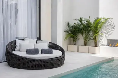 a living room with a wicker chair next to a pool at Brand New Luxury Design Villa by Amare Villas 2 in Badung