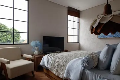 a bedroom with a bed and a chair and a television at Lavanya Villa Berawa beach in Canggu