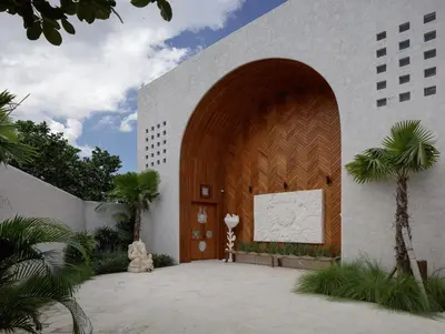 a building with a large wooden door and palm trees at Lavanya Villa Berawa beach in Canggu