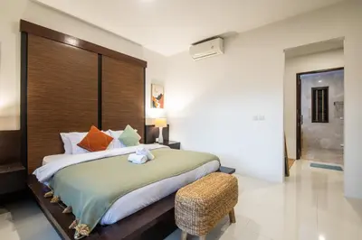 a bedroom with a large bed and a chair at Vase 2BR Villa Seminyak in Seminyak
