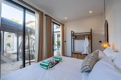 a bedroom with a white bed and a large window at La Vilaya Villa in Kerobokan