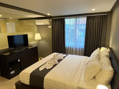 a bedroom with a large bed with a flat screen tv at Kooters Guesthouse Bali in Legian