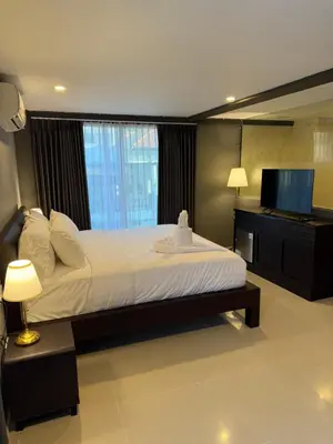a bedroom with a large bed and a flat screen tv at Kooters Guesthouse Bali in Legian