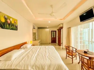 a bedroom with a white bed and a table at Jasmine Villa in Nusa Dua