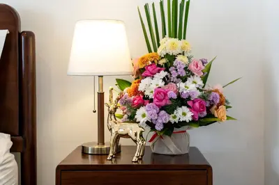 a vase of flowers on a table next to a lamp at Mich Bali Villa Two-Bedroom Private Pool Kuta in Seminyak