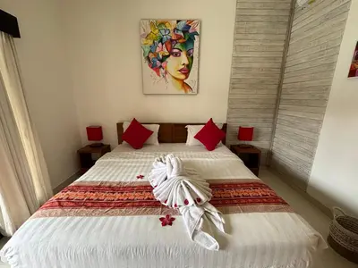a bedroom with a large bed with red pillows at Sirkus Guesthouse in Canggu