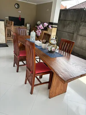 a wooden dining room table with chairs and flowers on it at Sirkus Guesthouse in Canggu